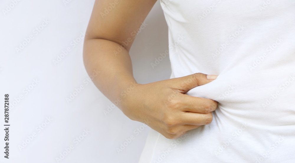 Close up fat Asian woman stand and hand squeeze her fat at belly on white wall have copy space. Concept overweight should diet to lose weight for health. Close up fat Asian woman stand and hand squeeze her fat at belly on white wall have copy space. Concept overweight should diet to lose weight for health.