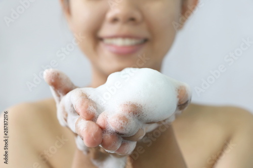 Close up white bubble foam on Asia young woman hand for cleansing her skin face or body. Side view.