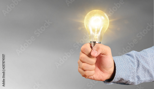 Hand of holding illuminated light bulb