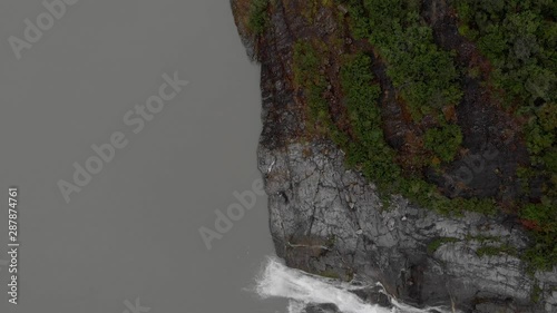 An aerial pan of the 300 ft. Nugget Falls waterfall, in Southeast Alaska. The fresh water from the falls mixes with the glacial water in the lake. photo