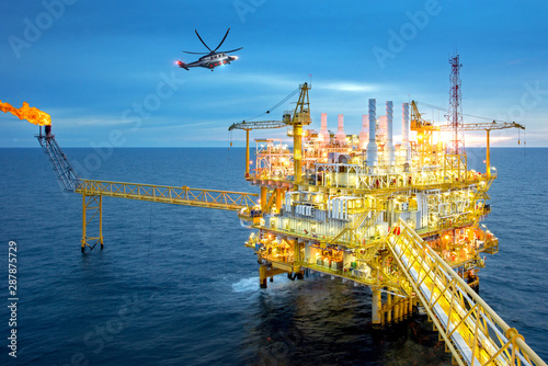 Offshore oil and gas rig platform with offshore helicopter transporting to oil rig at beautiful sky in the gulf of Thailand. photo
