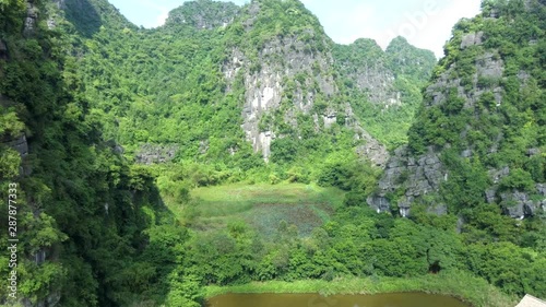 Aerial drone footage between karst mountains in the wonderful Unesco World Heritage site of Tam Coc, Ninh Binh in north Vietnam photo