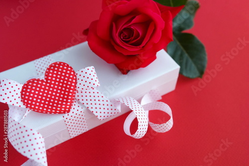 red rose and gift box on red background. Holiday concept. Copy space