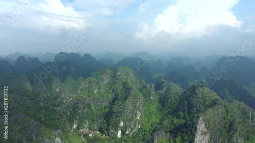 Drone footage around limestone mountains in the scenic landscape of Tam Coc, famous Unesco World Heritage in north Vietnam, a must to do for tourist. photo