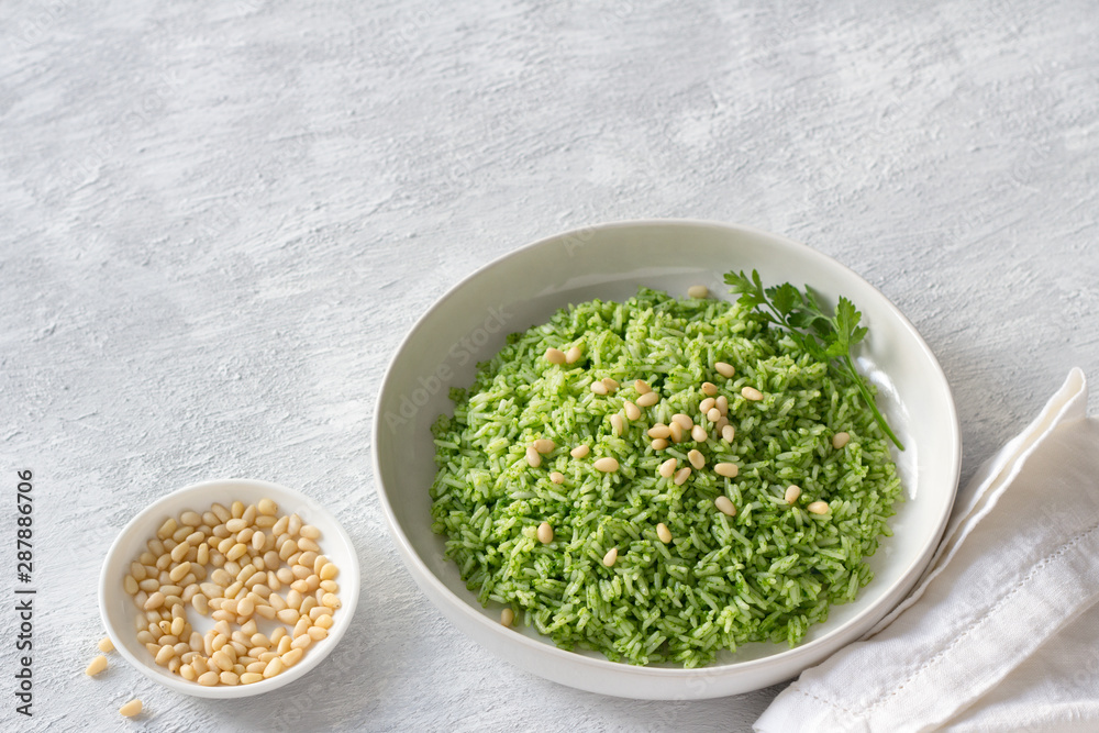 Vegan rice with green oil and pine nuts in a white bowl on a gray background, free space. delicious healthy homemade food Vegan rice with green oil and pine nuts in a white bowl on a gray background, free space. delicious healthy homemade food