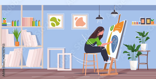 painter using paintbrush and palette woman artist sitting in front of easel art creativity hobby creative occupation concept modern workshop studio interior full length horizontal