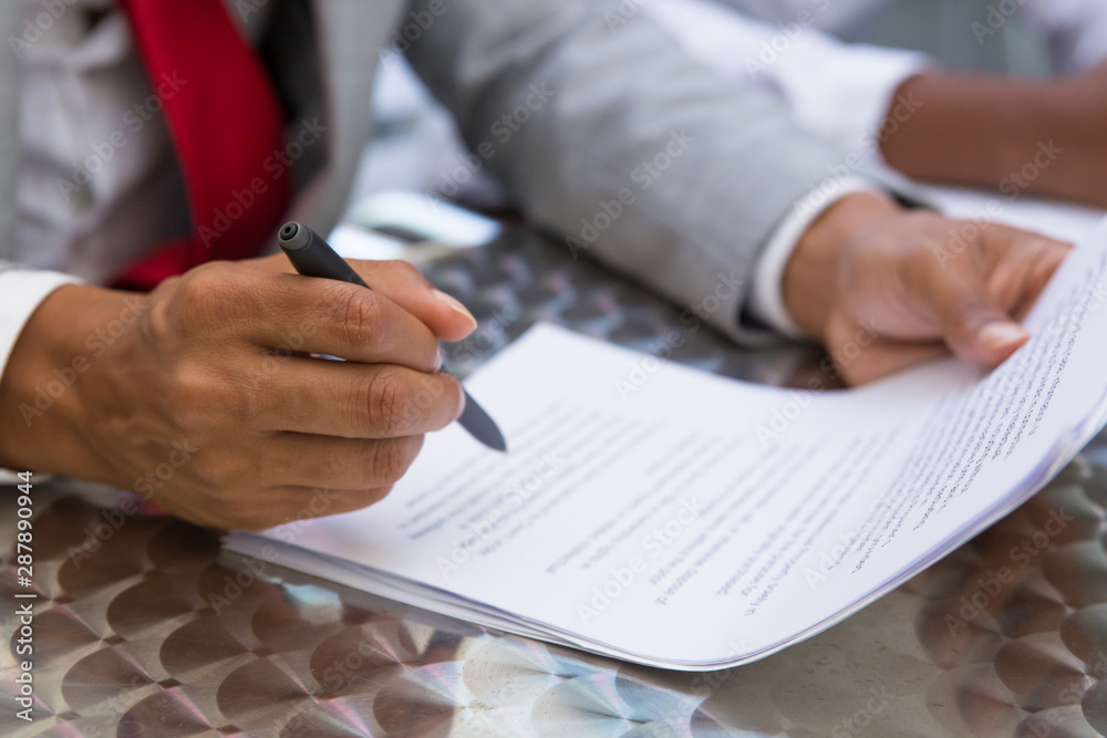 Businessman reading and checking contract text in street cafe. Closeup of document and business man hand holding pen. Signature concept Businessman reading and checking contract text in street cafe. Closeup of document and business man hand holding pen. Signature concept