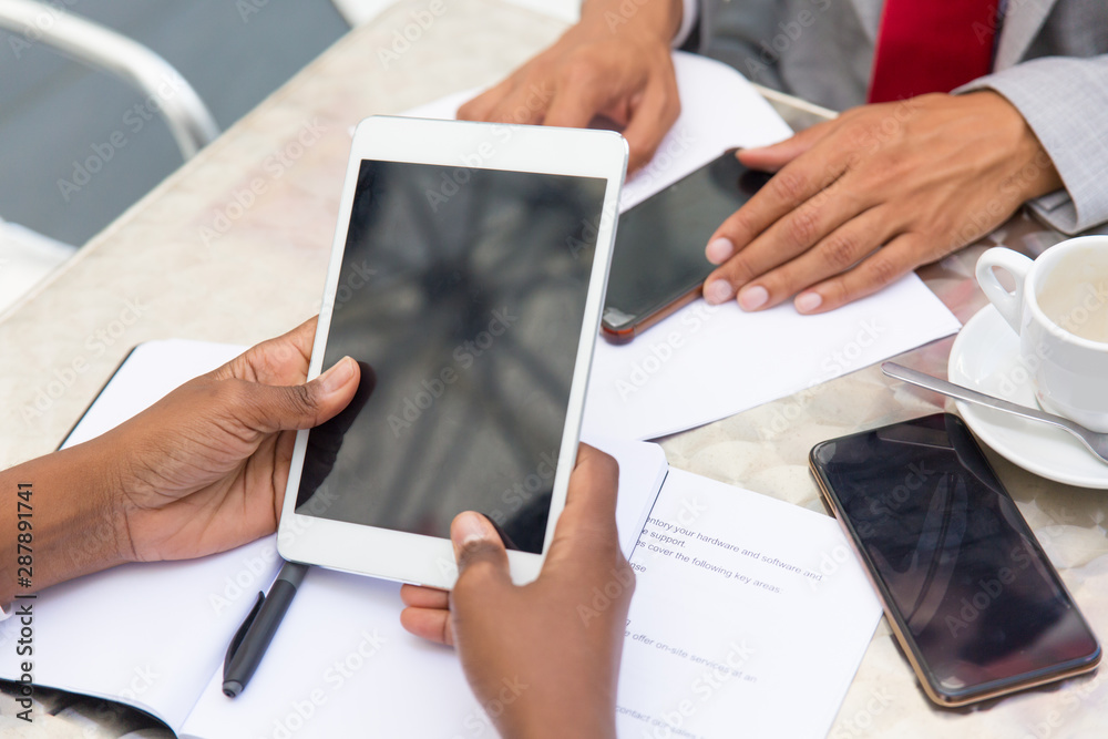 Tablet with blank screen in human hands. Dark skinned business woman holding digital device during meeting with partners. Communication or mobile computer concept Tablet with blank screen in human hands. Dark skinned business woman holding digital device during meeting with partners. Communication or mobile computer concept