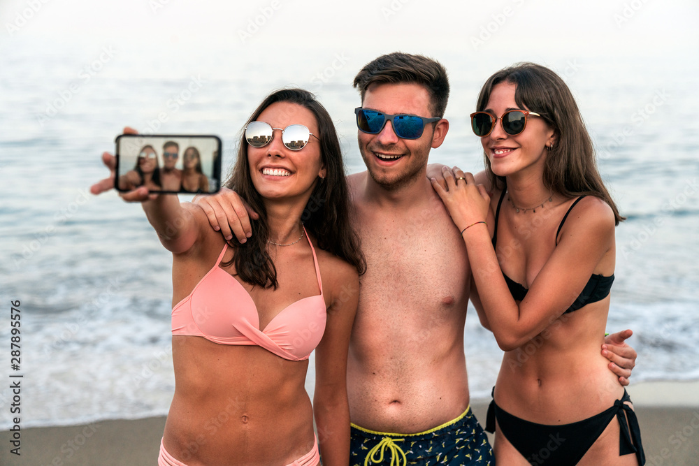 Young friends taking selfie on ocean seashore beach together