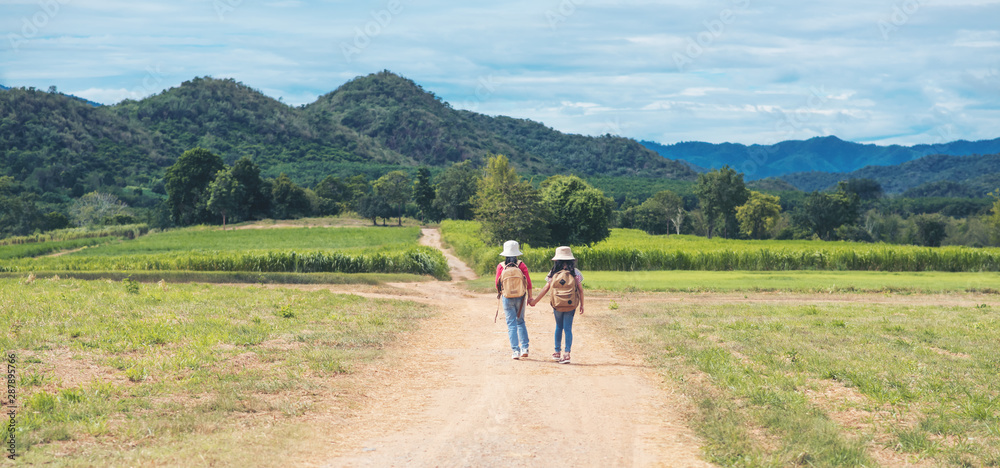 Fototapeta premium two asian little girl with backpack walking at natural park outdoor