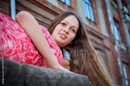 Brunette girl near red brick facade of old building in central part of city in summer day. Portrait of pretty girl on street © keleny