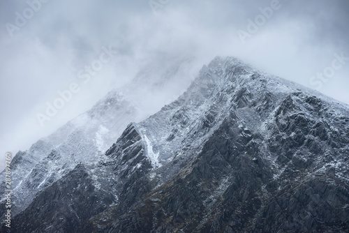 Stunning detail landscape images of snowcapped Pen Yr Ole Wen mountain in Snowdonia during dramatic moody Winter storm © veneratio