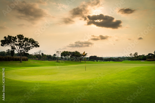 A view landscape green grass at golf course , big trees with black cloud sunlight rays sky background.