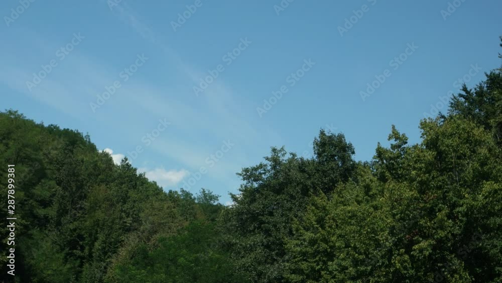 White clouds appear from behind a mountain covered with forest, time lapse White clouds appear from behind a mountain covered with forest, time lapse