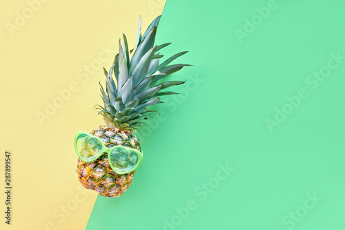 Funny pineapple in heart-shaped sunglasses on geometrc paper background photo