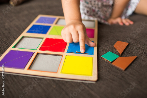 little girl's hands playing with a wood mosaic on a sofa. Educational games. Montessori Preschool early develop