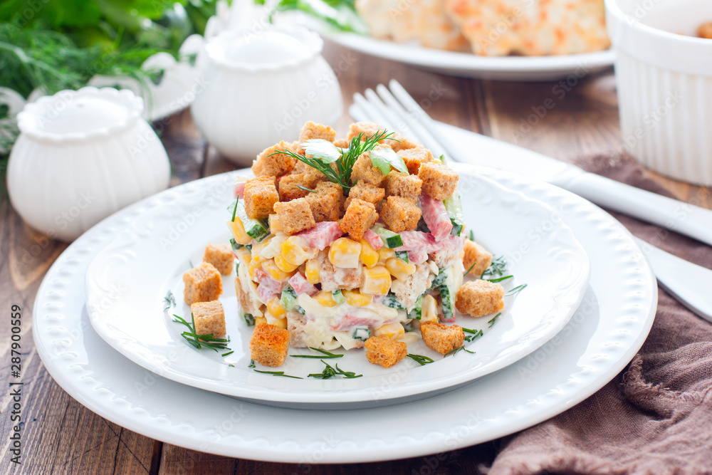 Salad with smoked sausage and crackers on a white plate in a portion serving, horizontal Salad with smoked sausage and crackers on a white plate in a portion serving, horizontal