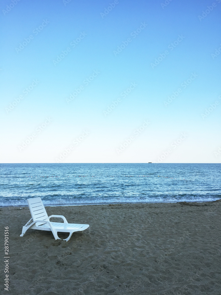 A lonely plastic lounge chair at the beach with seascape