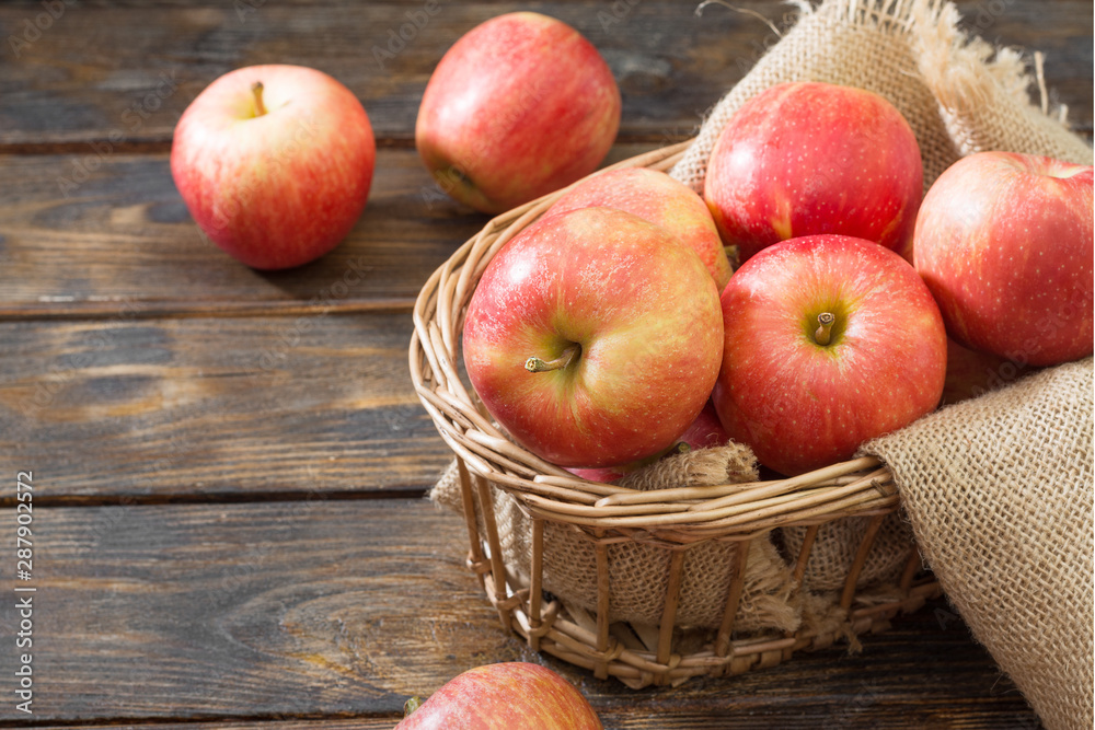 Red apples in a basket on a wooden table. Rustic style