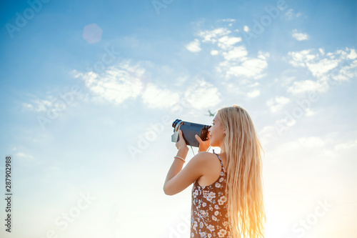 Bilde på lerret portrait of a blonde girl in a floral print dress with a vintage video camera in