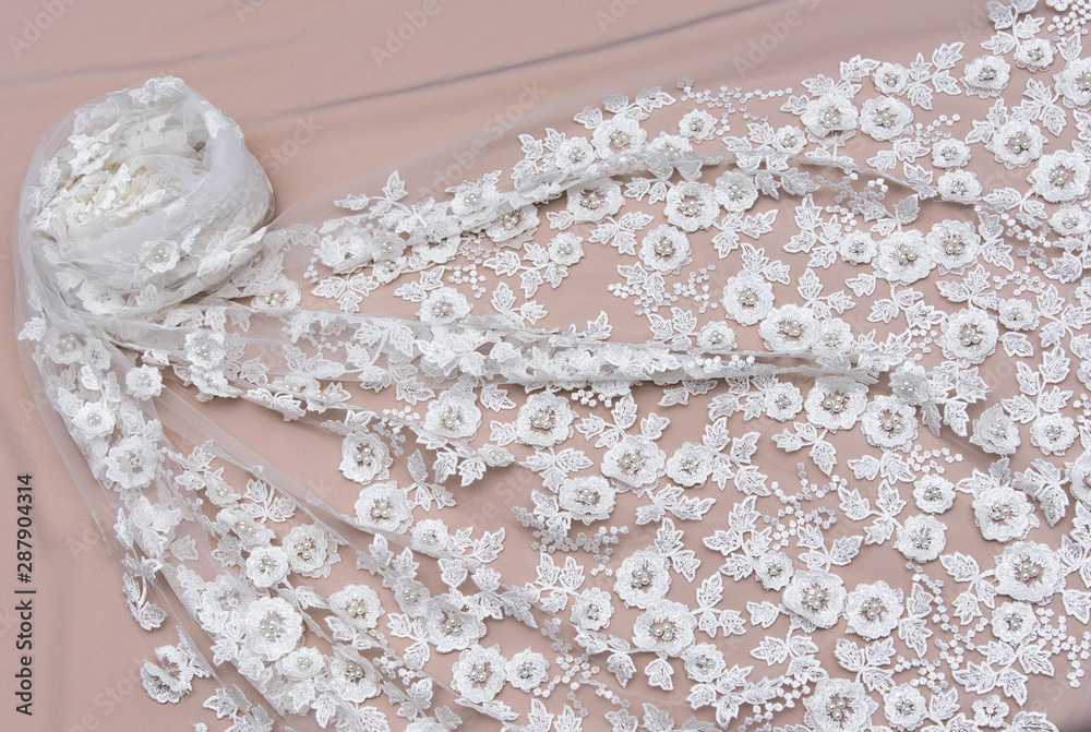 Texture lace fabric. lace on white background studio. thin fabric made of yarn or thread. a background image of ivory-colored lace cloth. White lace on beige background. Texture lace fabric. lace on white background studio. thin fabric made of yarn or thread. a background image of ivory-colored lace cloth. White lace on beige background.