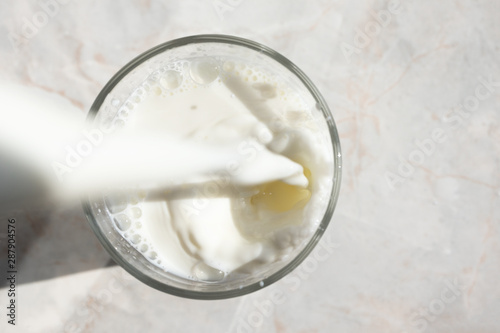 Close-up of fresh milk stream pouring into a glass with splash and bubbles