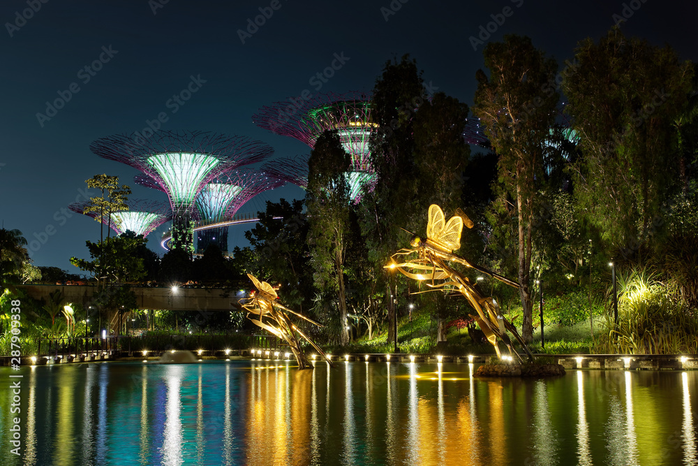 Landscape in the night - Singapore and Gardens by the Bay, colourful lights, water and the hotel in the shape of a boat