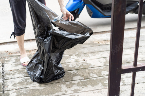 Asian Thai housewife is prepare the garbage plastic black bag at the fron of her house. photo