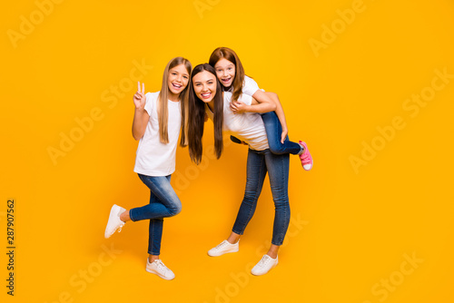 Photo of funky three ladies showing v-sign spending leisure time wear casual clothes isolated yellow background