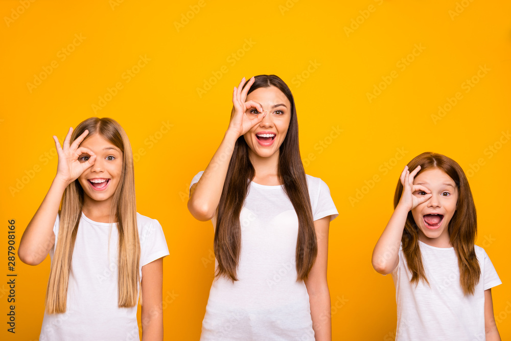 Funny three sister ladies holding hands in okey symbols near eye like specs wear casual outfit isolated yellow background Funny three sister ladies holding hands in okey symbols near eye like specs wear casual outfit isolated yellow background