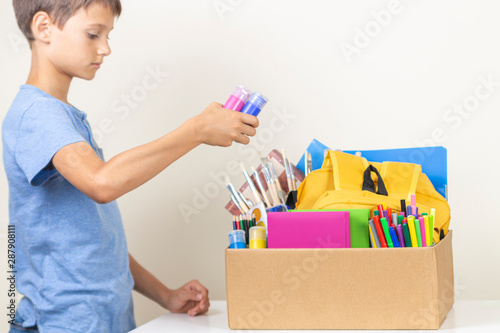 Donation concept. Kid preparing donate box with books, pencils and school supplies for donation