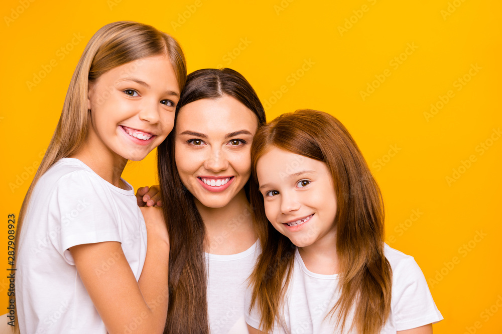 Three pretty ladies of different age hugging each other with love wear casual white t-shirts isolated yellow background Three pretty ladies of different age hugging each other with love wear casual white t-shirts isolated yellow background