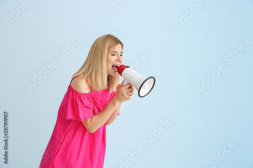 Screaming woman with megaphone on color background