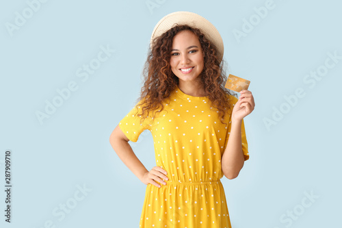 Happy African-American woman with credit card on light color background photo