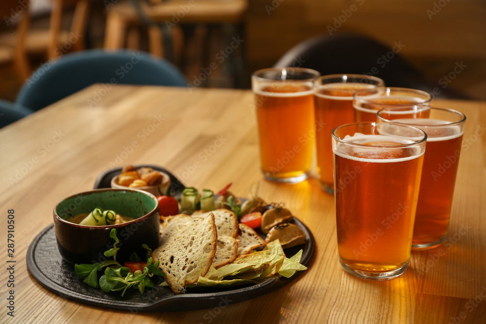 Glasses of fresh beer and snacks on table in pub Glasses of fresh beer and snacks on table in pub