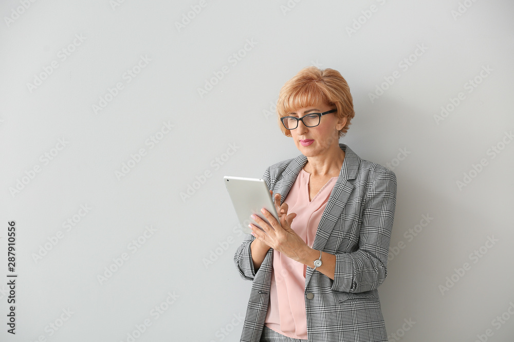 Portrait of beautiful middle-aged woman with tablet computer on light background Portrait of beautiful middle-aged woman with tablet computer on light background