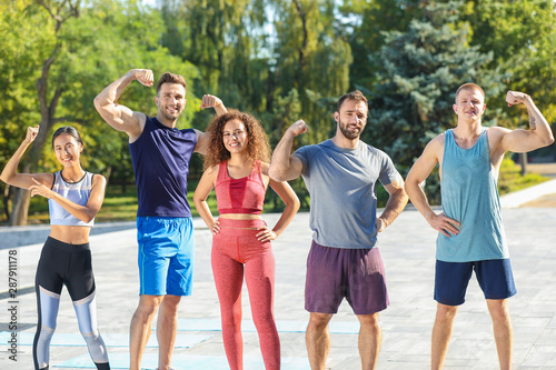 Group of young sporty people showing muscles outdoors