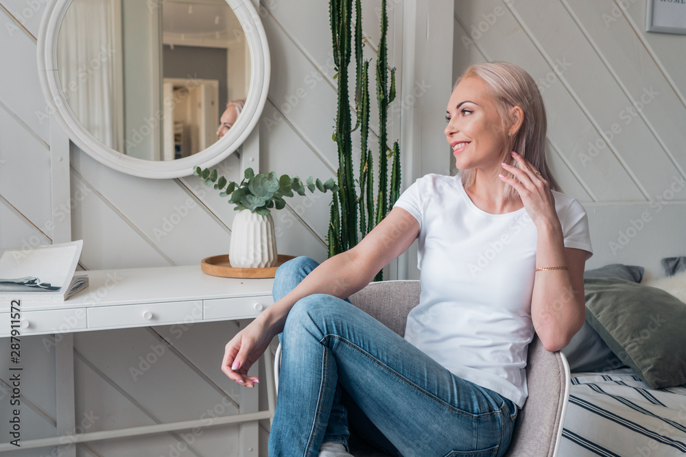 Beautiful blonde in casual clothes is sitting on a chair and dreaming Beautiful blonde in casual clothes is sitting on a chair and dreaming