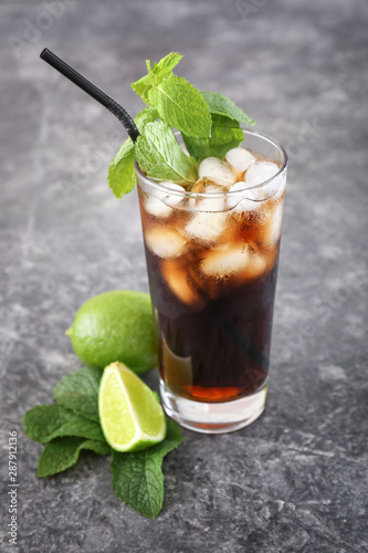 Glass of cold cola and lime on grey table