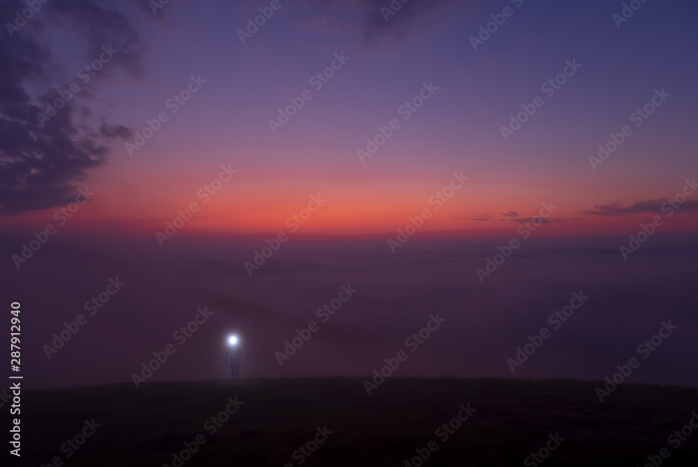 mountaineer with headlamp and walking on the mountain in the fog at dusk, Aiako Harriak natural park mountaineer with headlamp and walking on the mountain in the fog at dusk, Aiako Harriak natural park