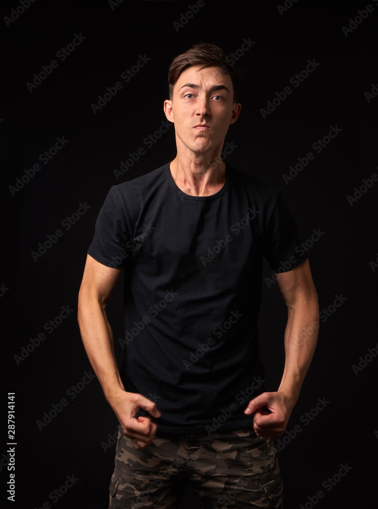 Fototapeta premium Angry and irritable man stands in the studio on a dark background