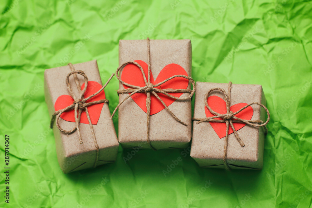 Set of gift boxes. Present wrapped in craft paper and tie hemp cord. Heart carton card. Green crumpled paper background. Set of gift boxes. Present wrapped in craft paper and tie hemp cord. Heart carton card. Green crumpled paper background.