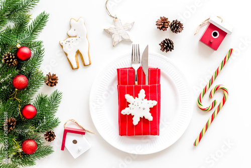 Table setting for new year with pine branch  decorations  candy cane  plate and tableware white background top view