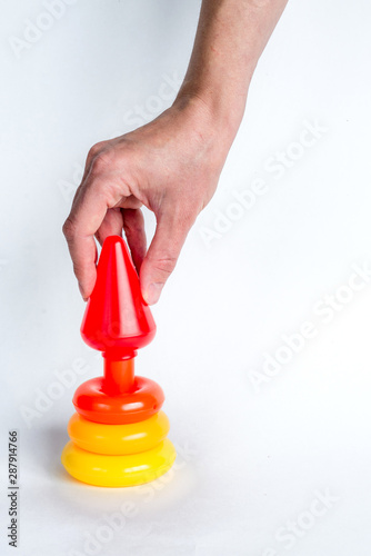 Construction of a colored children's pyramid on a white isolated background.. A woman's hand makes the final touch. Easy, simple and fast solution of a complex problem. Copy space