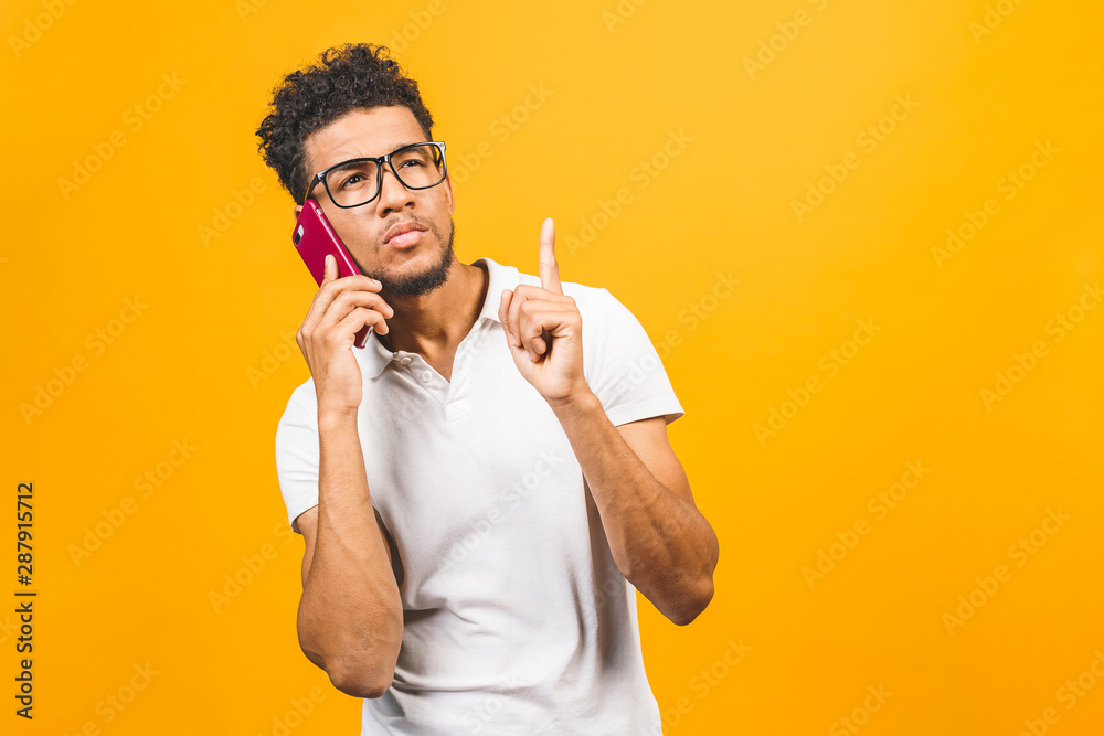 Portrait of a happy african american guy talking on mobile phone isolated against yellow background. Portrait of a happy african american guy talking on mobile phone isolated against yellow background.