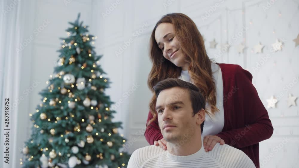 Closeup flirting wife massaging husband in christmas decorated room Closeup flirting wife massaging husband in christmas decorated room