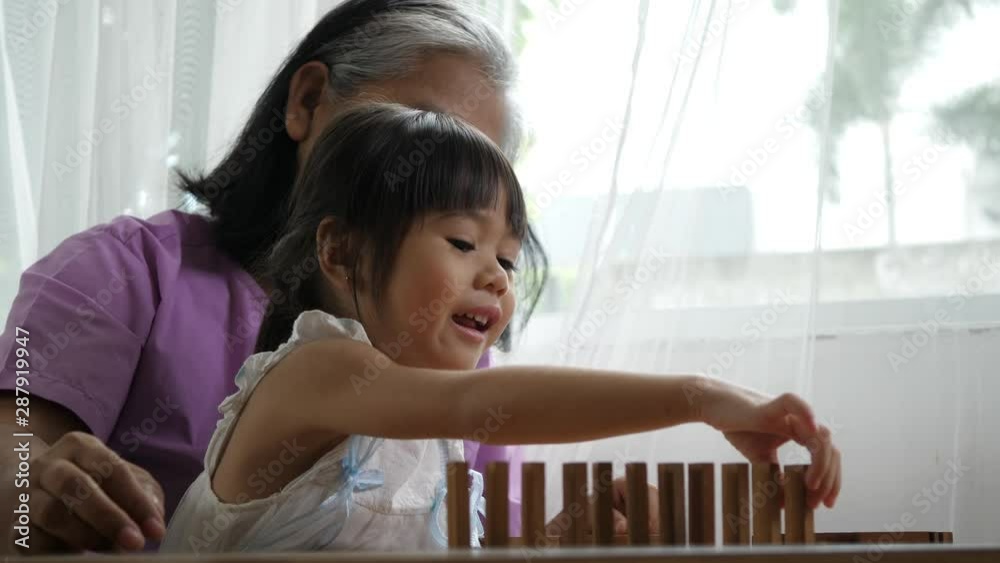 Grandmother and granddaughter stack play in a jenga blocks game