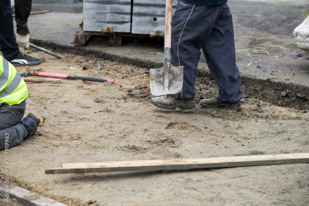 Close up of the gloved hands of a builder laying outdoor paving slabs on a prepared base. Close up of the gloved hands of a builder laying outdoor paving slabs on a prepared base.