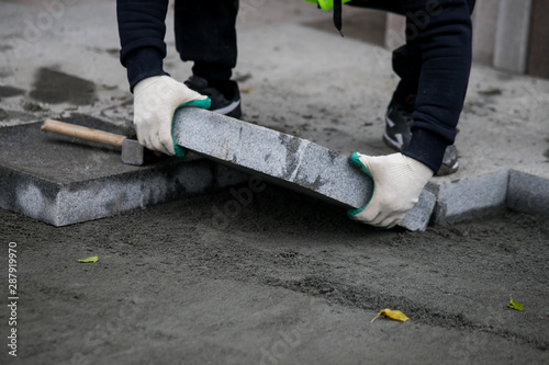 Close up of the gloved hands of a builder laying outdoor paving slabs on a prepared base. photo