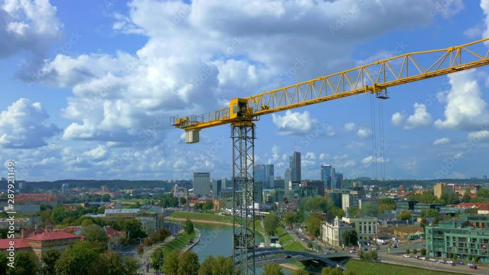 Tower construction crane turns the boom of crane on background of aerial city view of Vilnius, Lithuania. Tower construction crane turns the boom of crane on background of aerial city view of Vilnius, Lithuania.